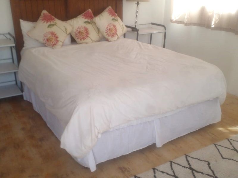 A bedroom featuring a wooden headboard and light-toned flooring, providing a functional space for rest.