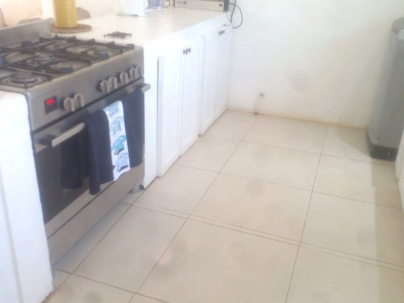 A functional kitchen area featuring built-in cabinetry, a gas stove with oven, and tiled flooring, requiring cosmetic updates to improve its overall condition.