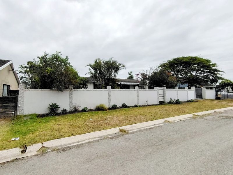 Street view of the property featuring a long perimeter wall with integrated pedestrian and driveway gates, providing privacy and security.