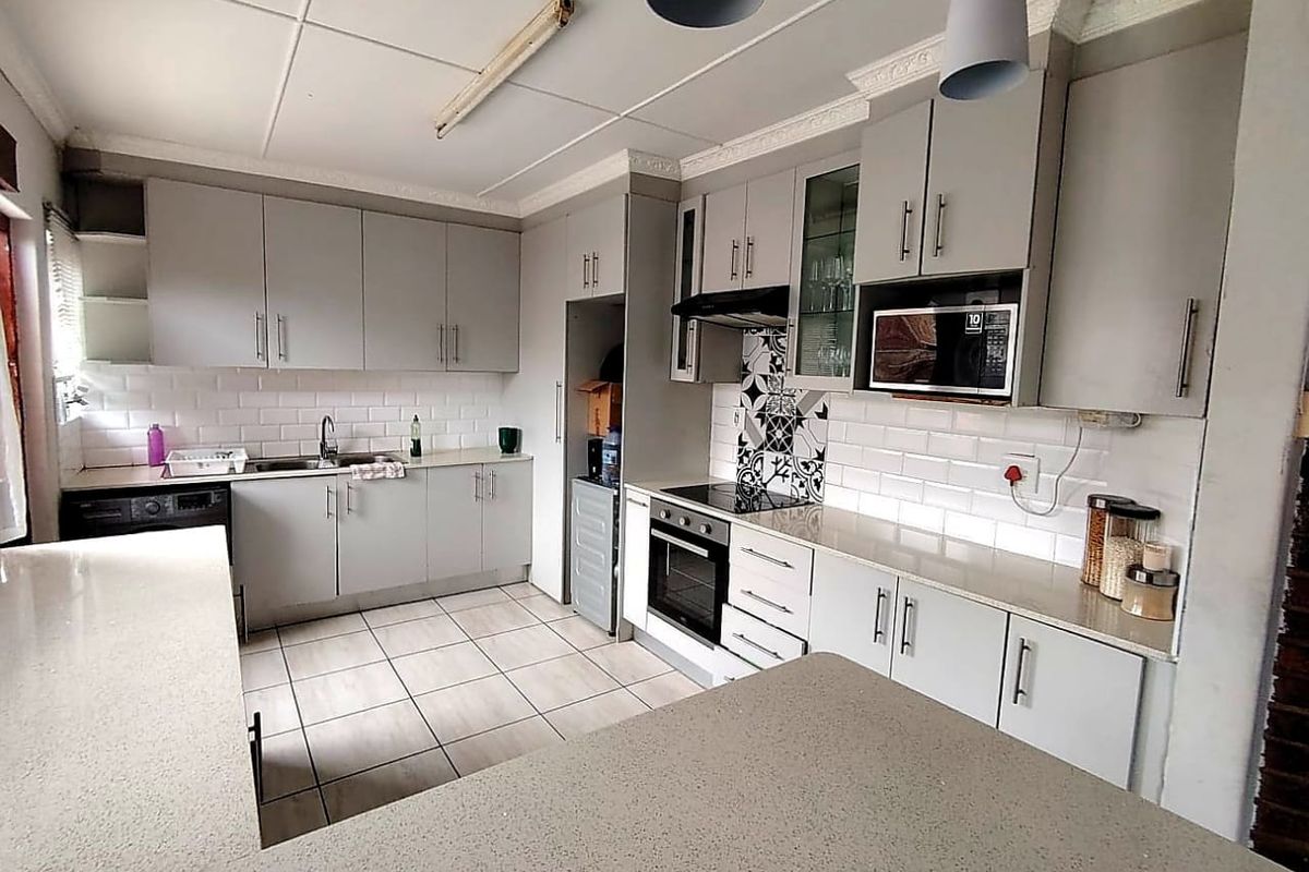Modernized kitchen featuring grey cabinetry, stone countertops, subway tile backsplash, and integrated appliances, offering a functional and clean cooking space.