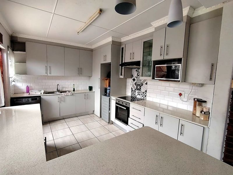 Modernized kitchen featuring grey cabinetry, stone countertops, subway tile backsplash, and integrated appliances, offering a functional and clean cooking space.