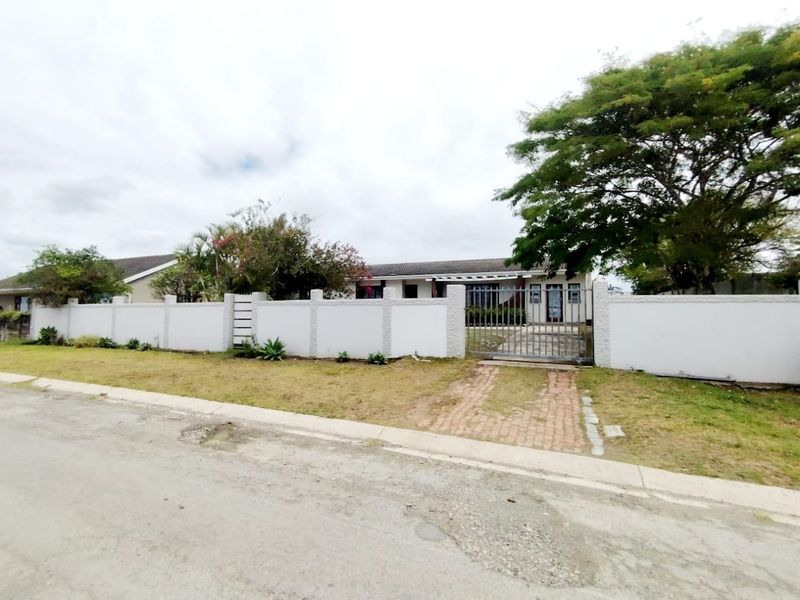 Front view of a residential property featuring a perimeter wall, metal gate, and paved driveway access.