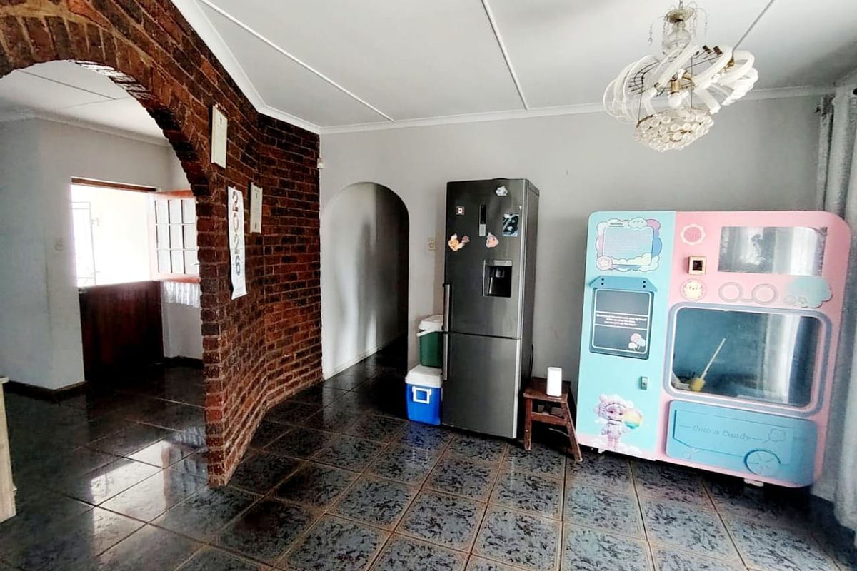 Living area featuring an exposed brick archway, tiled flooring, and a decorative chandelier, offering a unique architectural character with potential for modernization.