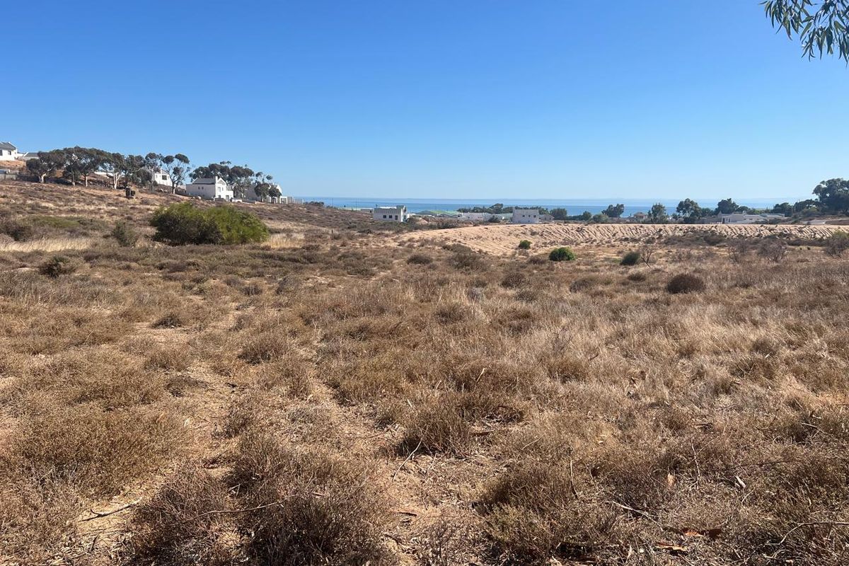 A wide-angle view of the vacant residential land featuring natural coastal vegetation and distant ocean views.