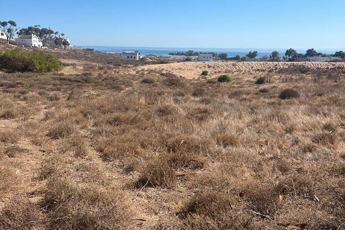 A wide-angle view of the vacant residential land, showcasing the natural landscape and distant ocean horizon.