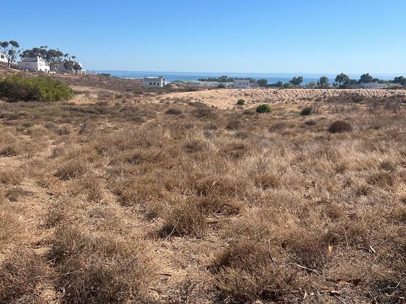 A wide-angle view of the vacant residential land, showcasing the natural landscape and distant ocean horizon.