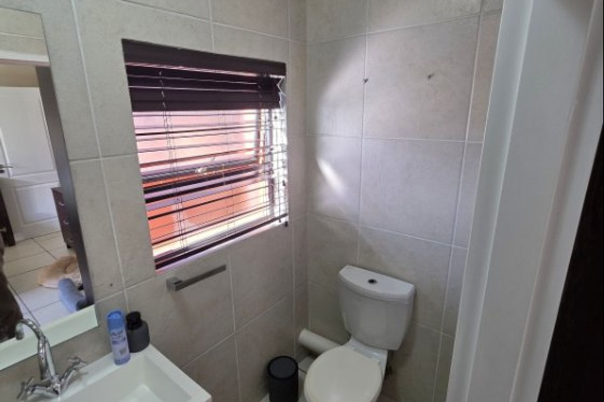 A compact guest bathroom featuring floor-to-ceiling tiling, a modern vanity basin, and a standard toilet.