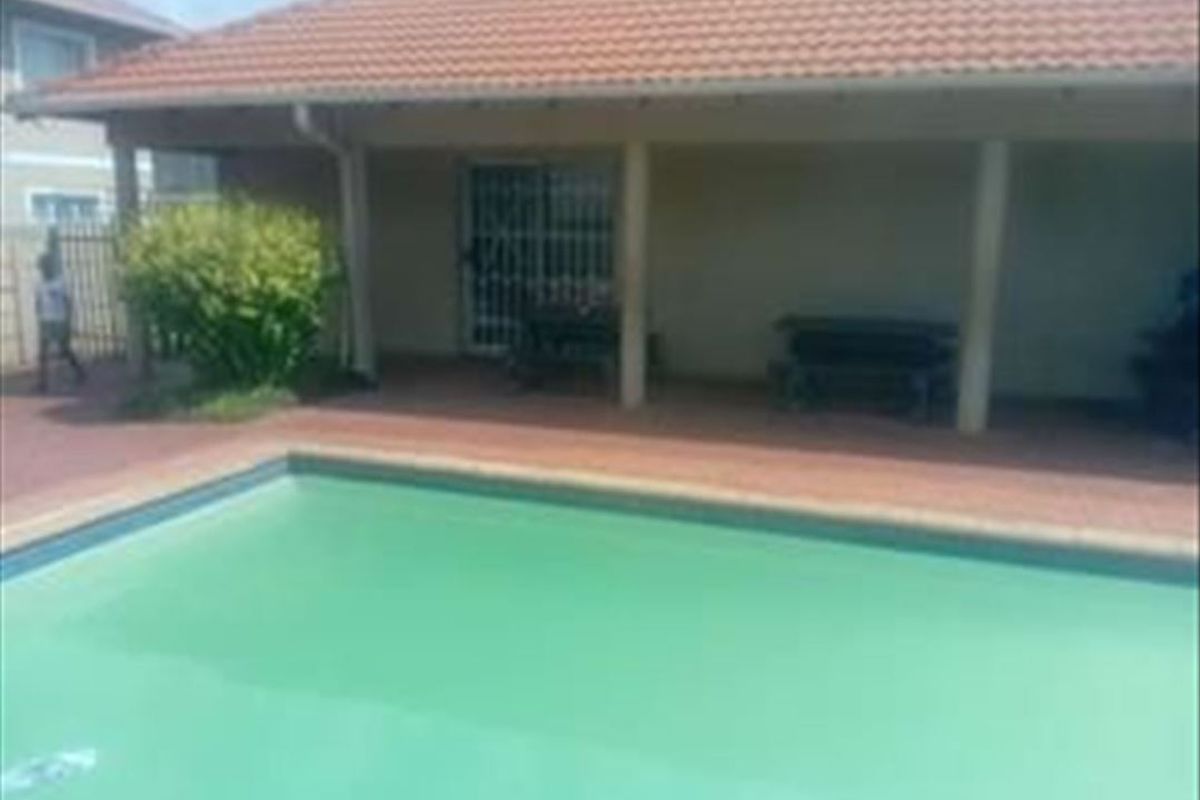 Outdoor pool area featuring a covered patio and tiled surround, providing a functional space for relaxation and entertainment.