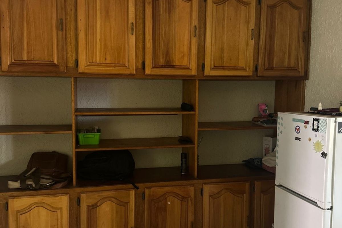 Kitchen area featuring extensive built-in wooden cabinetry and tiled flooring, offering significant storage space with a dated aesthetic.