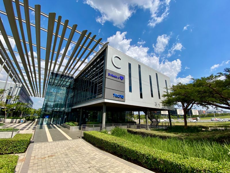 Modern commercial office building featuring a glass facade, metal louvered canopy, and well-maintained landscaped grounds.