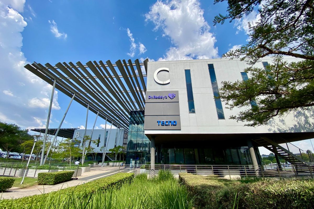 Modern commercial building facade featuring a prominent architectural canopy, glass curtain walls, and well-maintained landscaped surroundings.