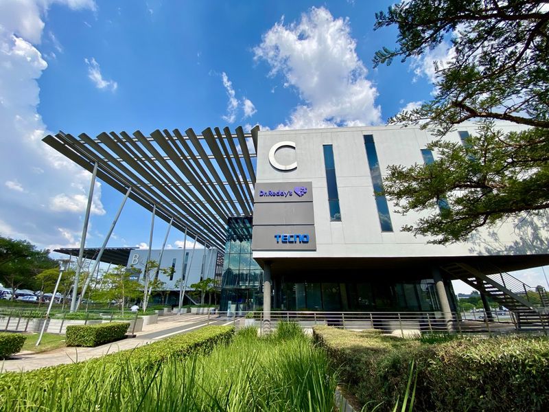 Modern commercial building facade featuring a prominent architectural canopy, glass curtain walls, and well-maintained landscaped surroundings.
