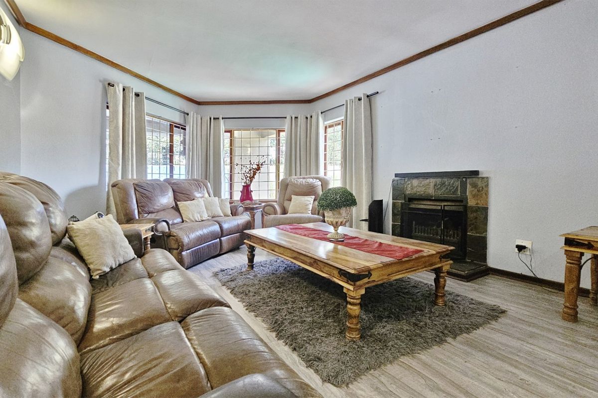 A comfortable living room featuring a stone-clad fireplace, bay windows, and laminate flooring, offering a cozy and functional space for relaxation.