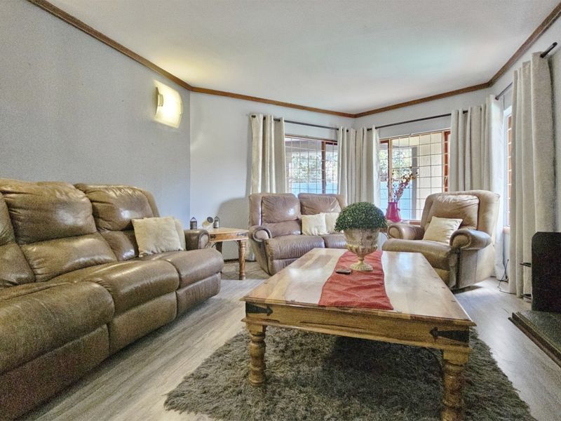 A comfortable living room featuring laminate flooring, wall-mounted lighting, and a fireplace, offering a cozy space for relaxation.