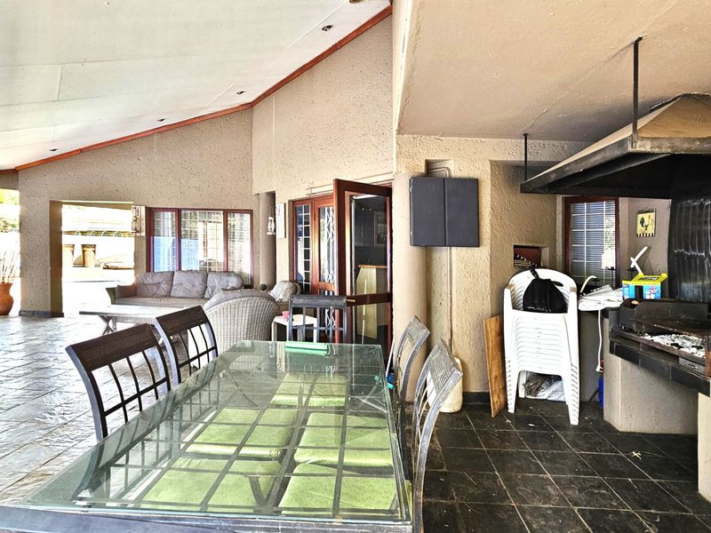 Spacious covered patio featuring a built-in braai area with an extractor hood and durable tiled flooring, ideal for outdoor entertaining.