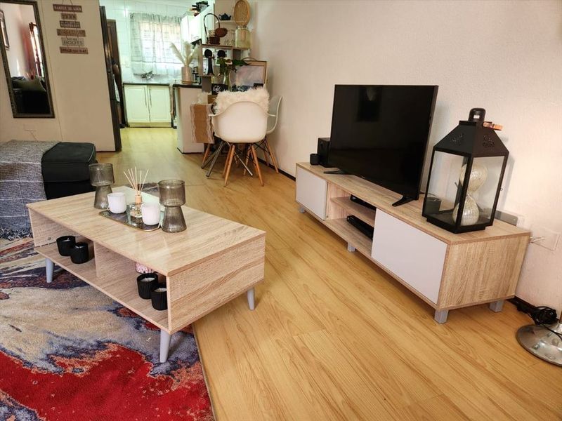Open plan living area featuring light wood-look laminate flooring and a view through to the kitchen area.