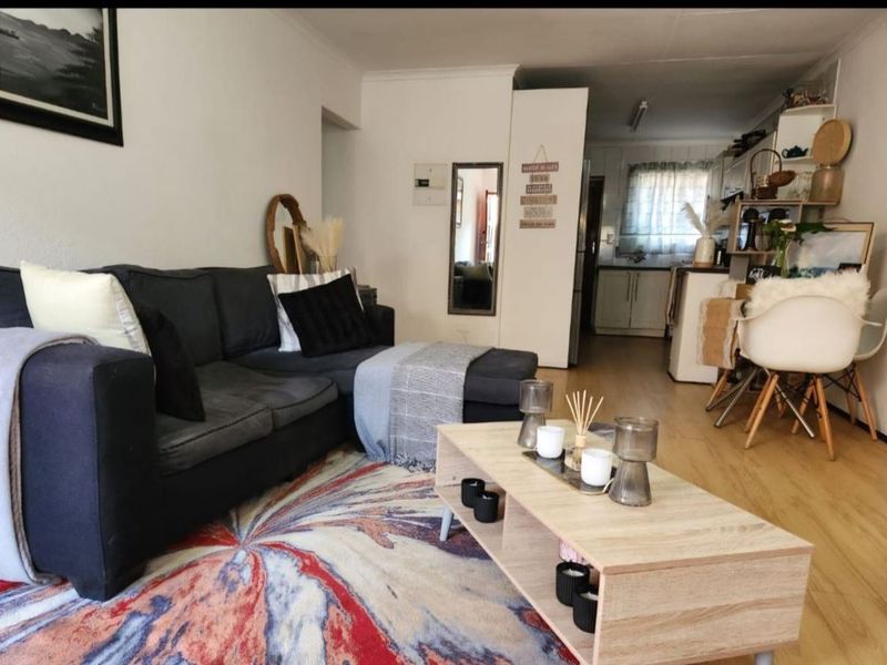 Open plan living area featuring light wood-look flooring and a seamless transition into the kitchen space.