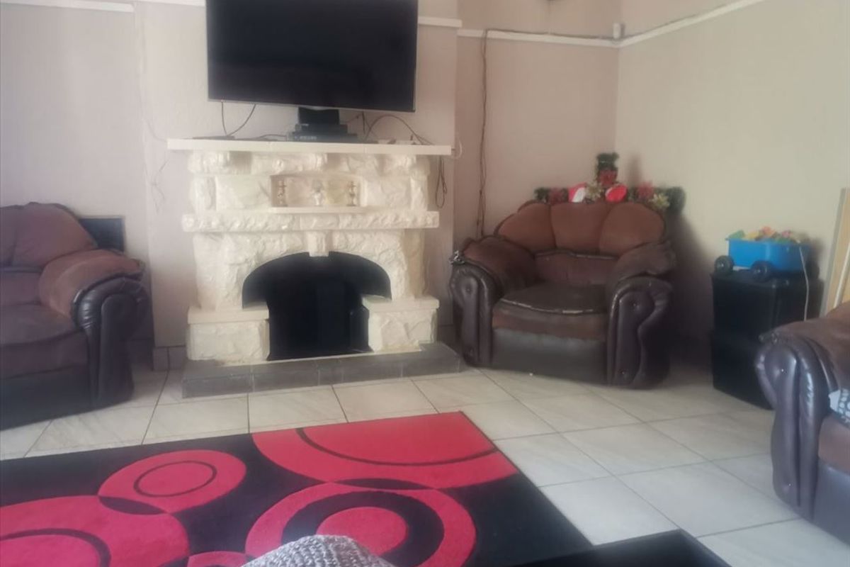 A living room featuring a prominent stone fireplace and tiled flooring, providing a central focal point for the space.