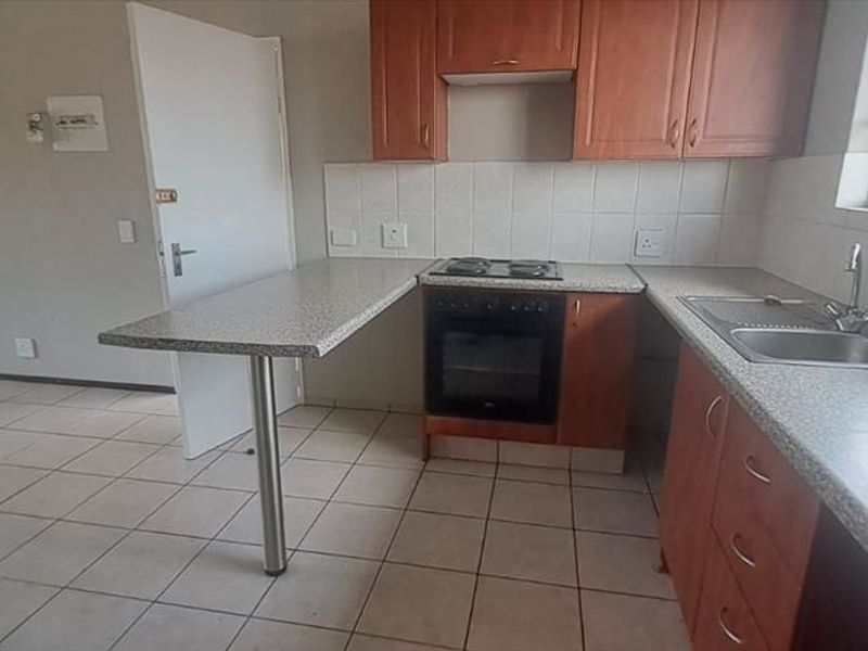 A functional kitchen featuring built-in wooden cabinetry, laminate countertops, an integrated oven and hob, and tiled flooring, offering a clean and practical workspace.