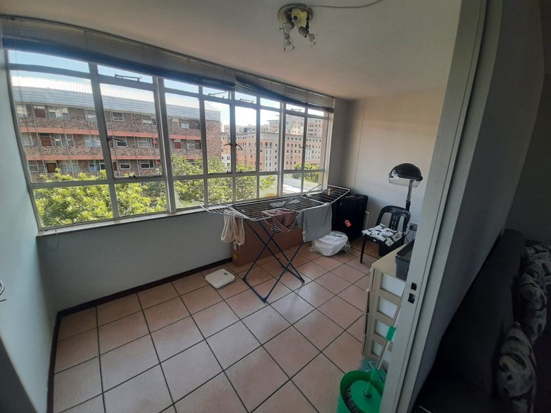 Enclosed balcony area featuring large windows with urban views and tiled flooring, offering potential as a sunroom or additional living space.