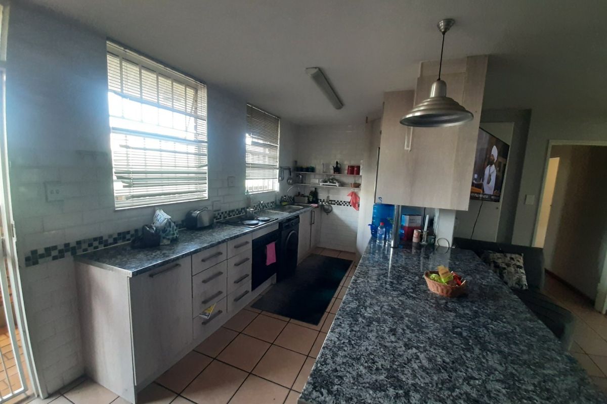 Functional kitchen featuring granite countertops, built-in oven, hob, and tiled flooring with an integrated breakfast bar area.