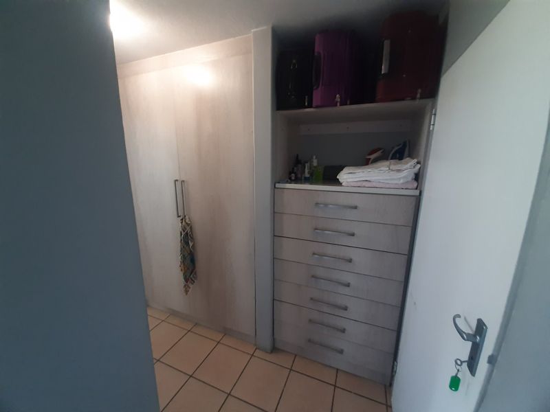 A bedroom area featuring built-in cupboards and a set of integrated drawers with tiled flooring.