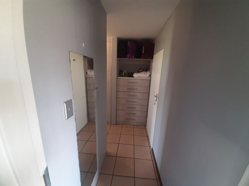 A functional hallway featuring tiled flooring and built-in storage cabinetry with integrated drawers and shelving.