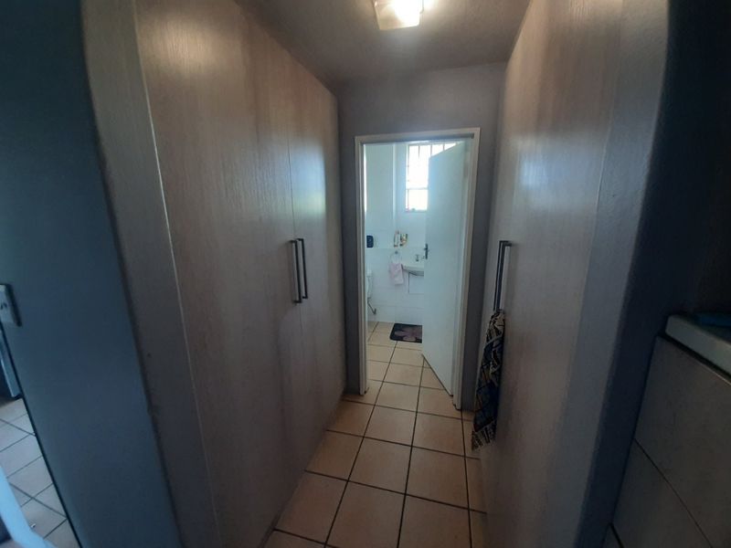A functional hallway featuring built-in cupboards for storage, tiled flooring, and direct access to an adjacent bathroom.