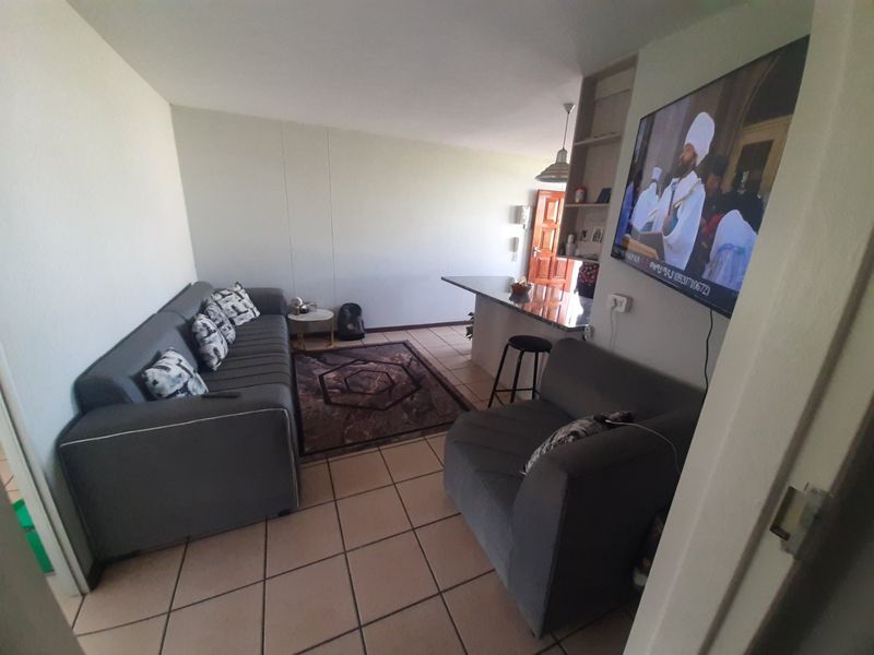 Open-plan living area featuring tiled flooring, a granite breakfast bar, and built-in shelving, creating a functional and connected space.