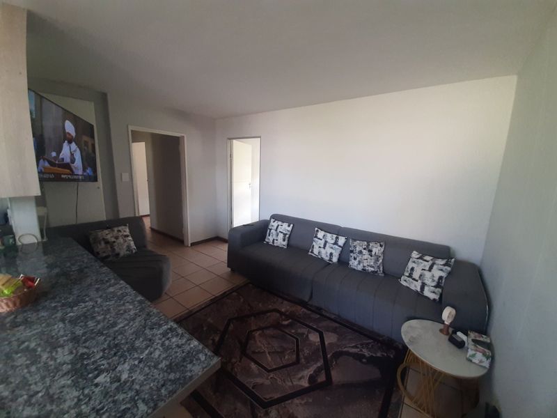 Open plan living area featuring tiled flooring and a granite kitchen breakfast bar, creating a functional and connected space.