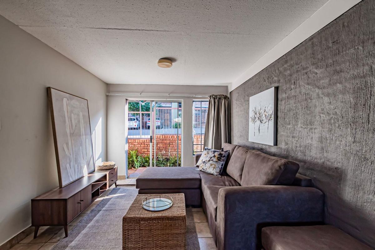 A comfortable living room featuring a textured accent wall, tiled flooring, and a sliding glass door providing access to the exterior.