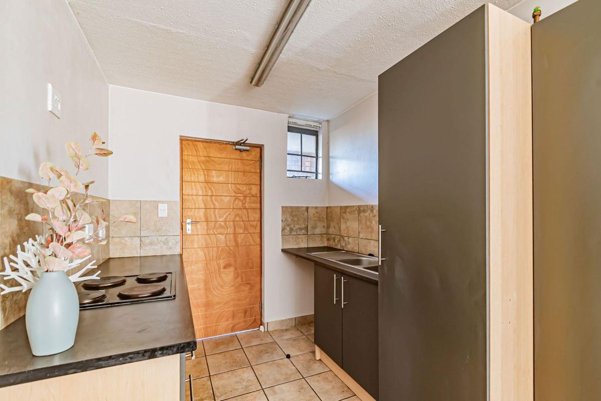 Compact kitchen featuring built-in cabinetry, laminate countertops, an electric hob, and tiled flooring with a functional layout.