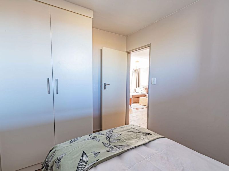 A bedroom featuring a built-in wardrobe and a doorway leading to an adjacent living area.