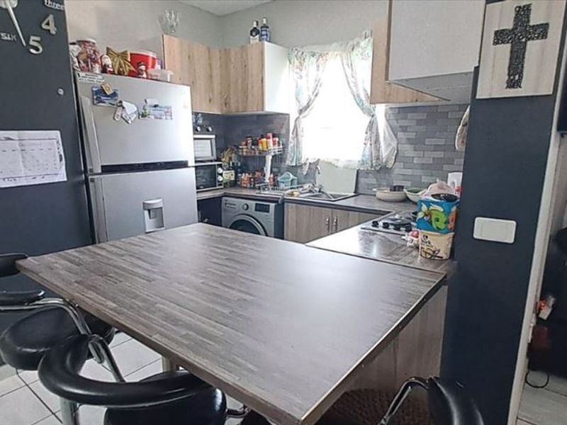 A functional kitchen featuring wood-look cabinetry, a tiled backsplash, a built-in hob, and an integrated breakfast bar area.