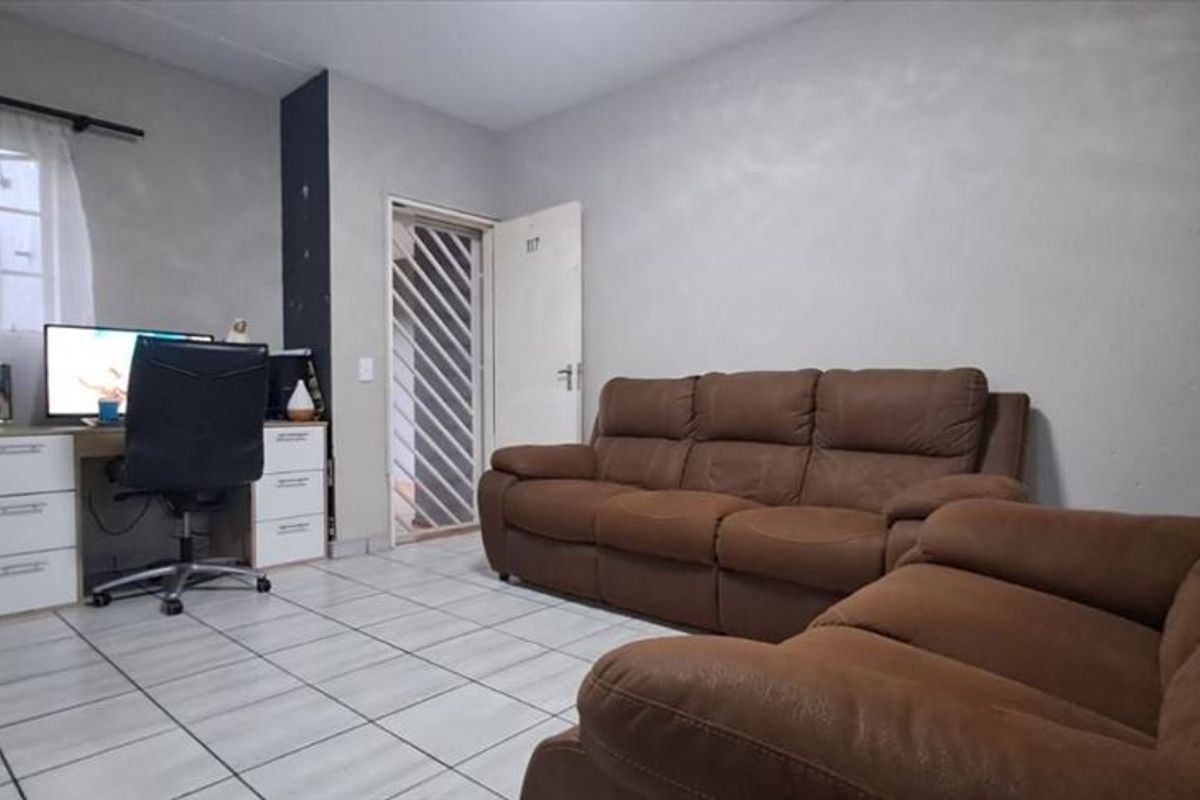 A living room featuring tiled flooring and a security gate at the entrance, providing a functional and secure living space.