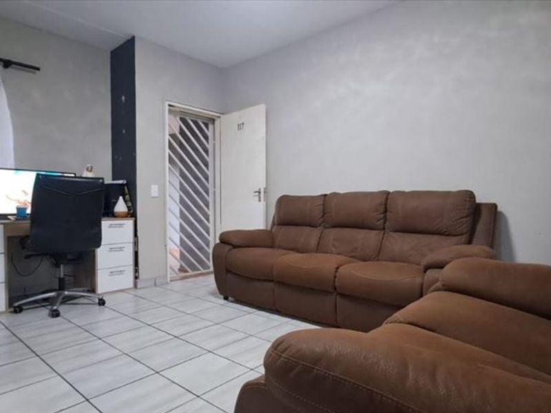 A living room featuring tiled flooring and a security gate at the entrance, providing a functional and secure living space.