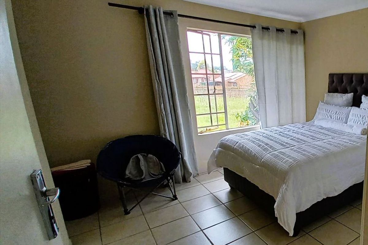 A bedroom featuring tiled flooring and a window with security bars, providing natural light and a view of the exterior.