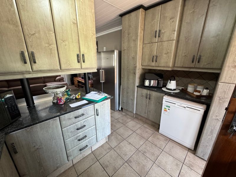 A functional kitchen featuring granite countertops, ample laminate cabinetry, and tiled flooring, providing a practical workspace with integrated storage solutions.