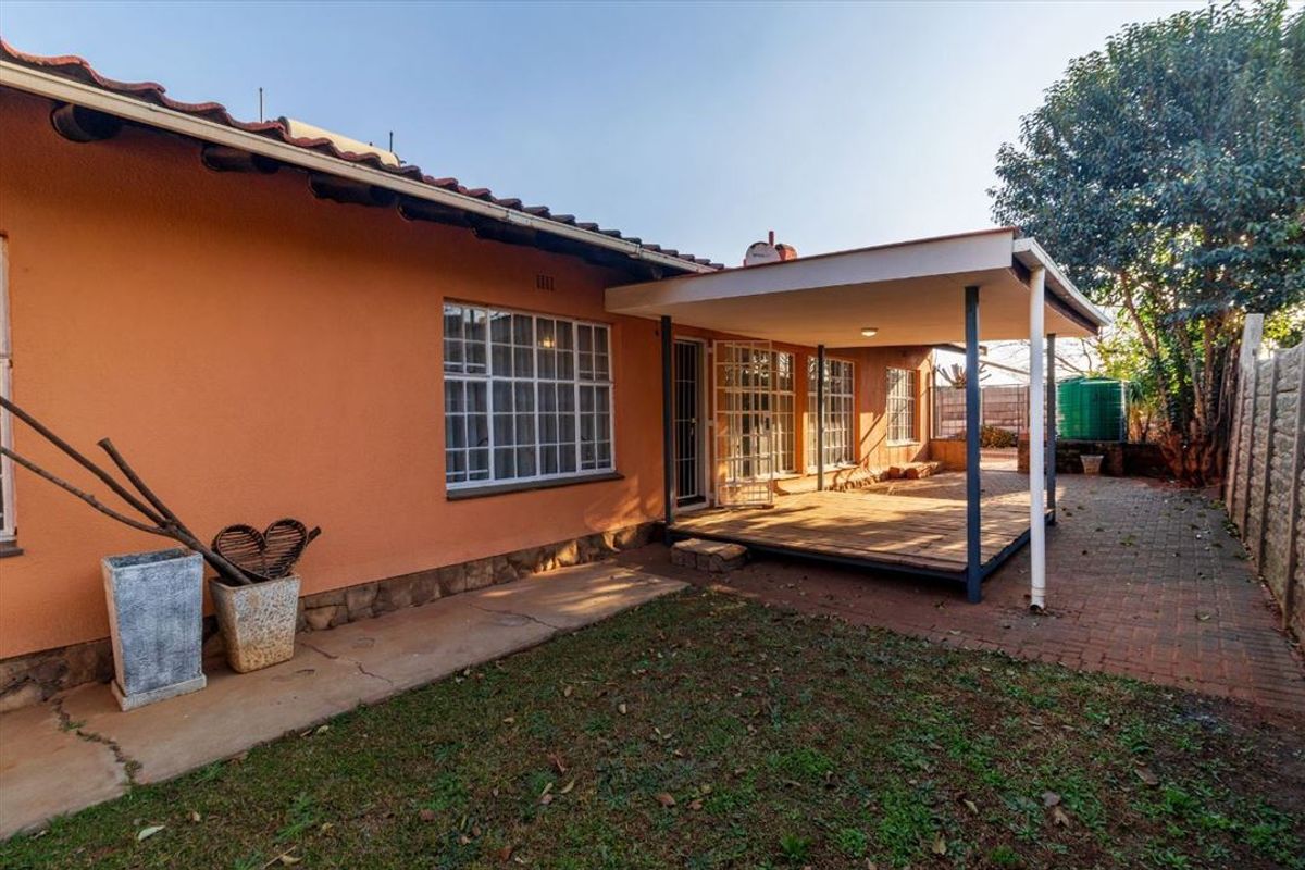 Rear view of the property featuring a covered patio area, brick paving, and a garden space with a water tank.