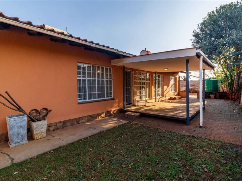 Rear view of the property featuring a covered patio area, brick paving, and a garden space with a water tank.