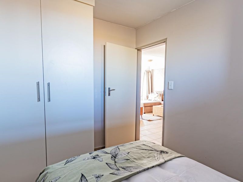 A bedroom featuring a built-in wardrobe with white cabinetry and a doorway leading to an adjacent living area.