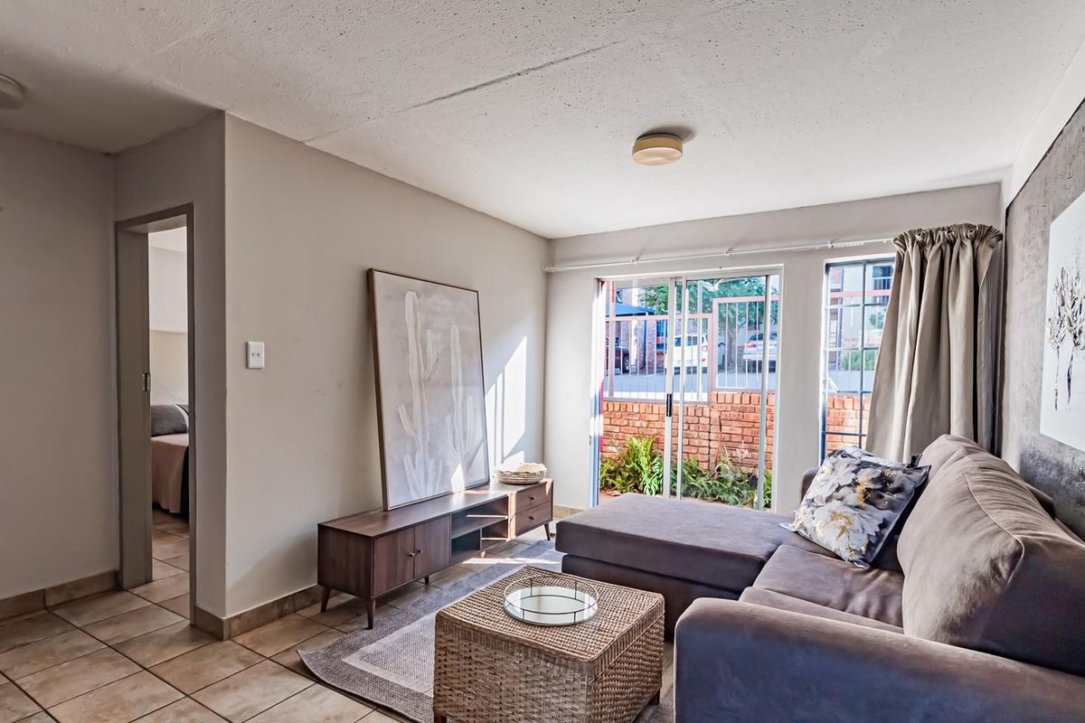 A living room featuring ceramic floor tiles, a textured ceiling, and a sliding glass door providing access to an outdoor area.
