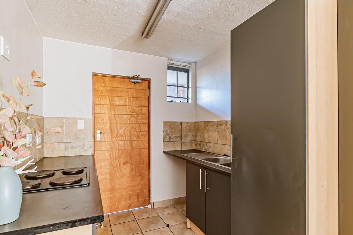 A functional kitchen featuring built-in cabinetry, a hob, tiled backsplash, and tiled flooring, providing a practical workspace for daily cooking needs.