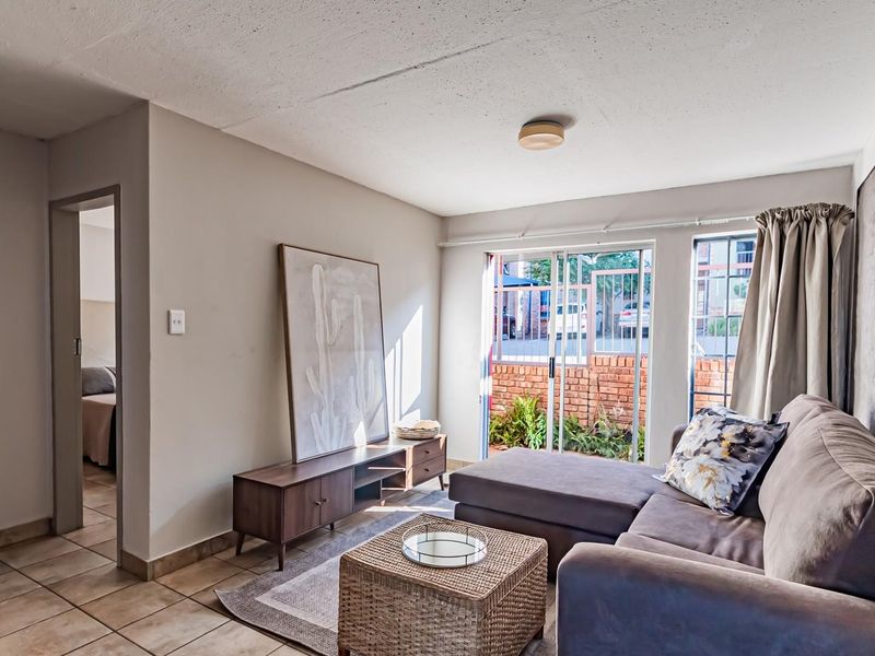 A living room featuring tiled flooring, a textured ceiling, and a sliding glass door providing access to an outdoor area.