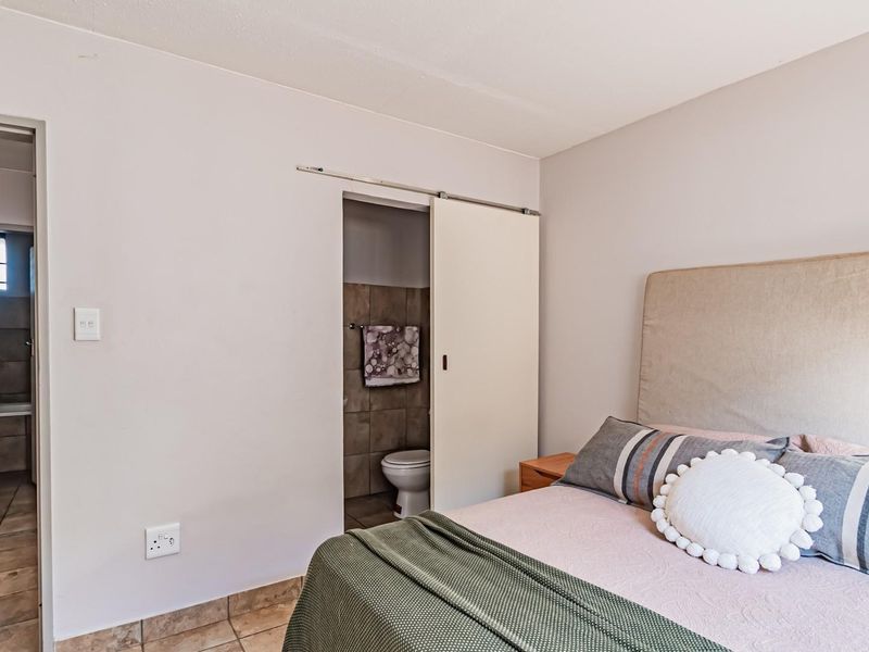 Bedroom featuring tiled flooring and a sliding door providing direct access to an en-suite bathroom.