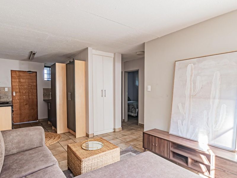 Open-plan living area featuring tiled flooring, built-in cabinetry, and neutral wall finishes, providing a functional and versatile space.