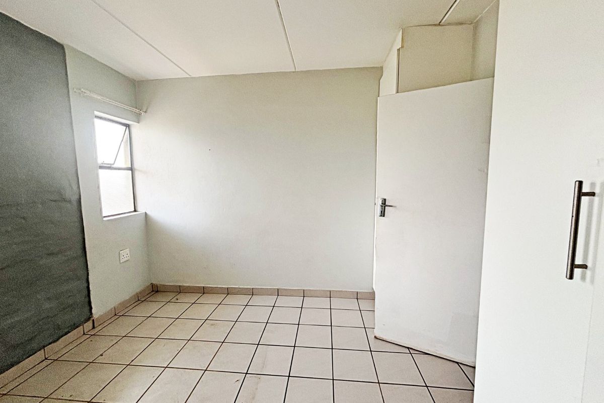 An empty bedroom featuring tiled flooring, a built-in cupboard, and a single window, offering a blank canvas for renovation or interior design.