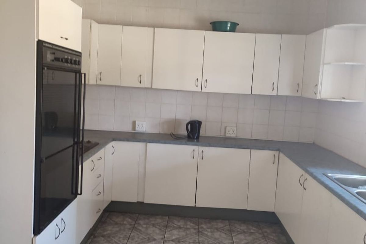 A functional kitchen featuring white built-in cabinetry, laminate countertops, a built-in oven, and tiled flooring with a neutral tiled backsplash.