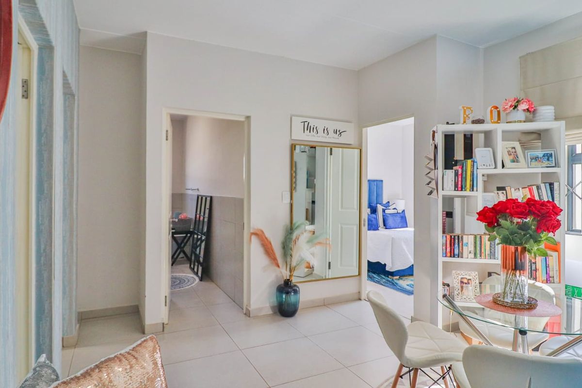 A bright living area featuring neutral tiled flooring and access to adjacent rooms, providing a functional and well-maintained space.