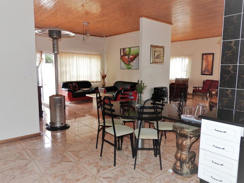 Spacious open-plan living and dining area featuring a timber ceiling, tiled flooring, and a functional kitchen with granite countertops.